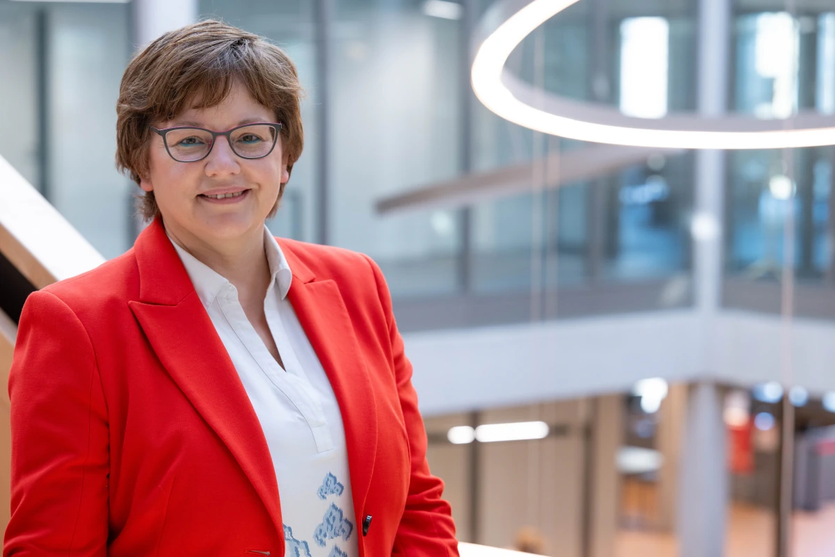 Businessportrait Berlin Potsdam — Frau mit rotem Blazer und Brille in modernem Bürogebäude