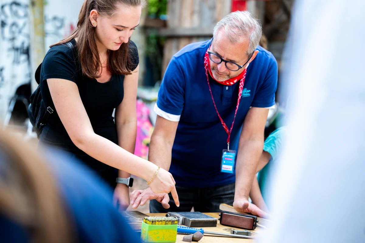 Eventfotografie Berlin – Tag des Handwerks im Mellowpark: ein Aussteller erklärt einer Jugendlichen ein Gewerk